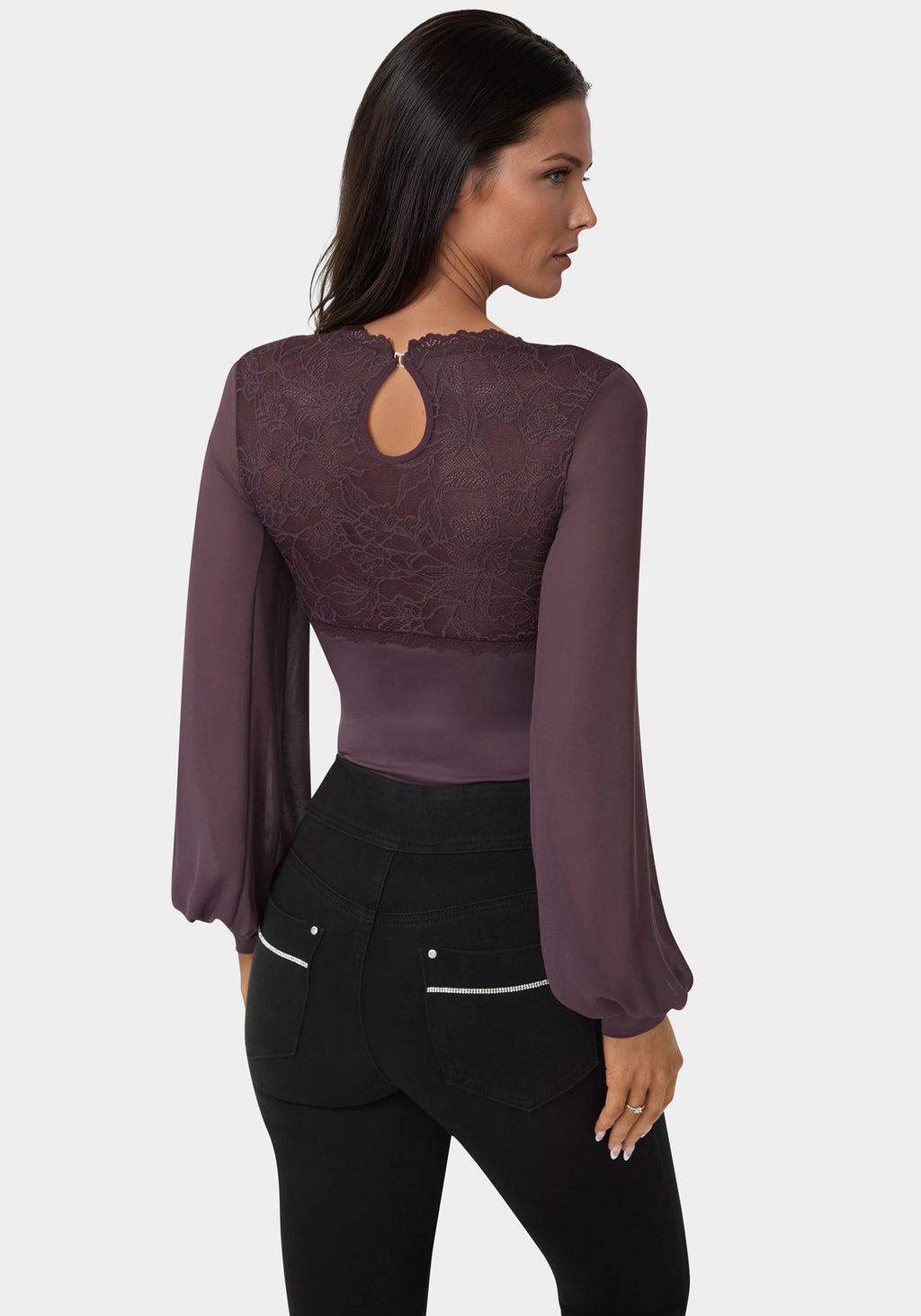 Woman wearing a purple blouse with a cut-out back design on a white background