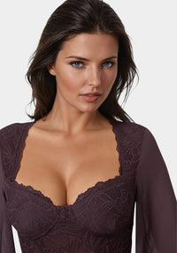Woman wearing a dark purple lace dress against a white background