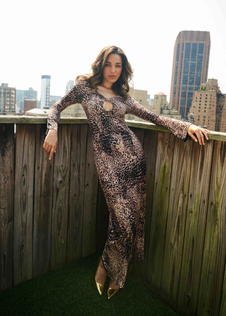 Woman in a lepoard dress standing on a rooftop with city skyline in the background